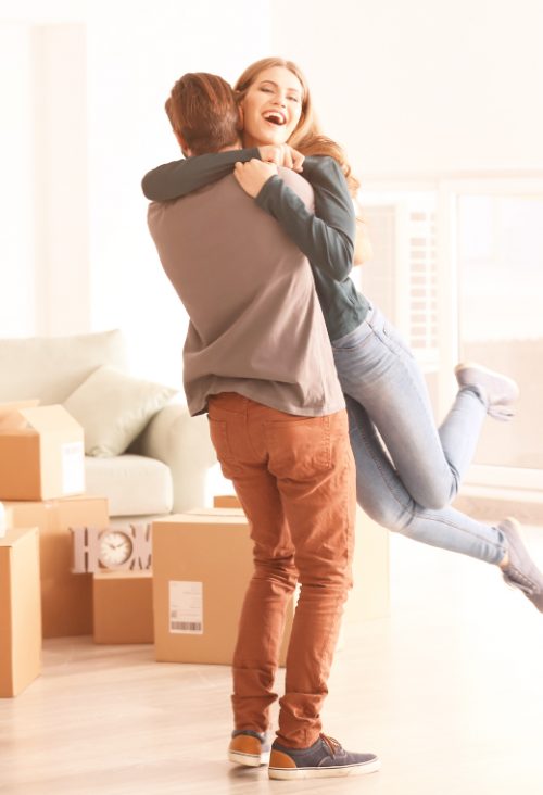 young happy couple in room with moving boxes at new home