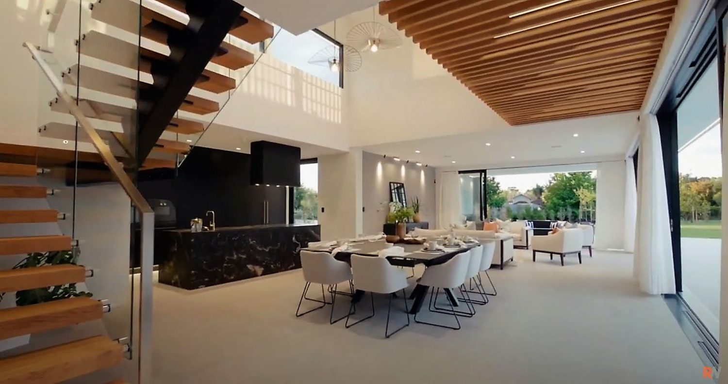 Interior of modern home with open plan dining area and black marble kitchen island with stairs
