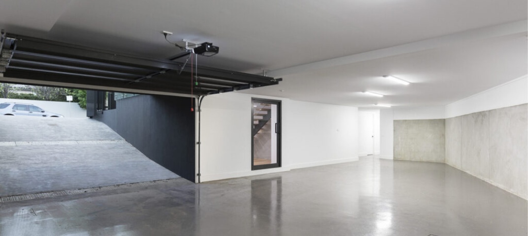 Garage with ramp leading down onto polished concert floors with white walls